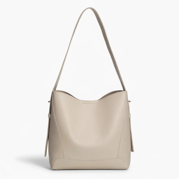 Amara Vegan Leather Bucket Bag in off-white, front studio view showcasing minimalist bucket silhouette and wide shoulder strap