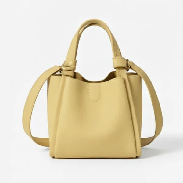 Arden Genuine Leather Bucket Bag in off-yellow, front studio view showcasing compact bucket shape, top handles, and crossbody strap