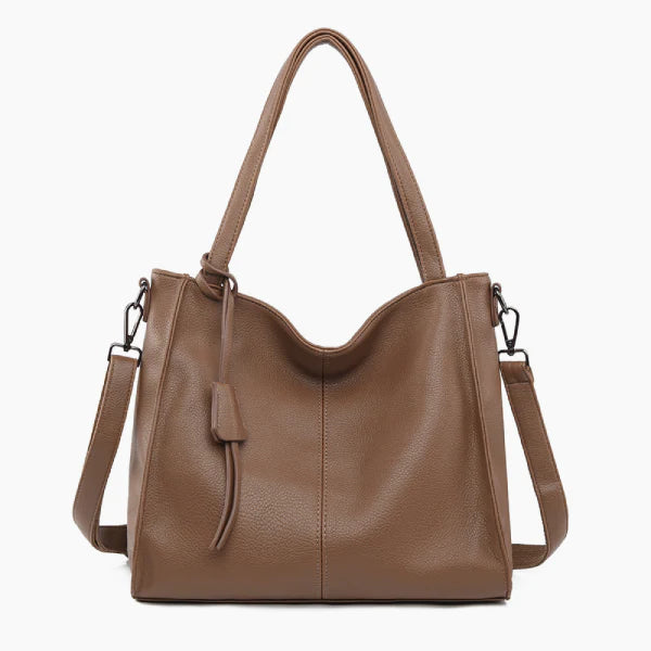 Front view of a brown vegan leather tote bag featuring a minimalist design with a central tassel detail and elegant handles