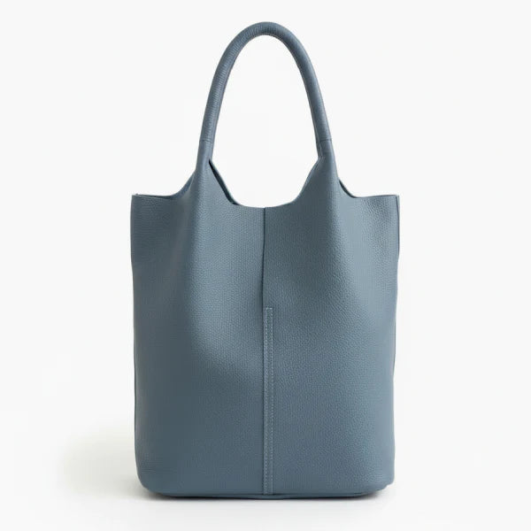Front view of blue cowhide leather tote bag with minimalist design, featuring a central seam and sturdy handles