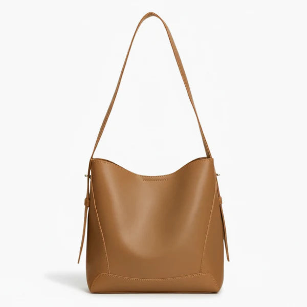 Amara Vegan Leather Bucket Bag in brown, front studio view showcasing minimalist bucket silhouette and wide shoulder strap