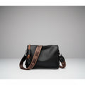 Auralis Genuine Cowhide Crossbody Bag in black, front studio view showcasing rectangular silhouette, zip-top closure, and patterned adjustable strap