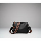 Auralis Genuine Cowhide Crossbody Bag in black, front studio view showcasing rectangular silhouette, zip-top closure, and patterned adjustable strap