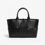 Front view of Aurelia black genuine leather tote bag with woven texture and leather handles, featuring a minimalistic design