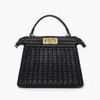 Front view of black woven vegan leather satchel bag with gold clasp and structured design