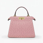 Front view of pink woven vegan leather satchel bag with gold clasp, handle, and structured design