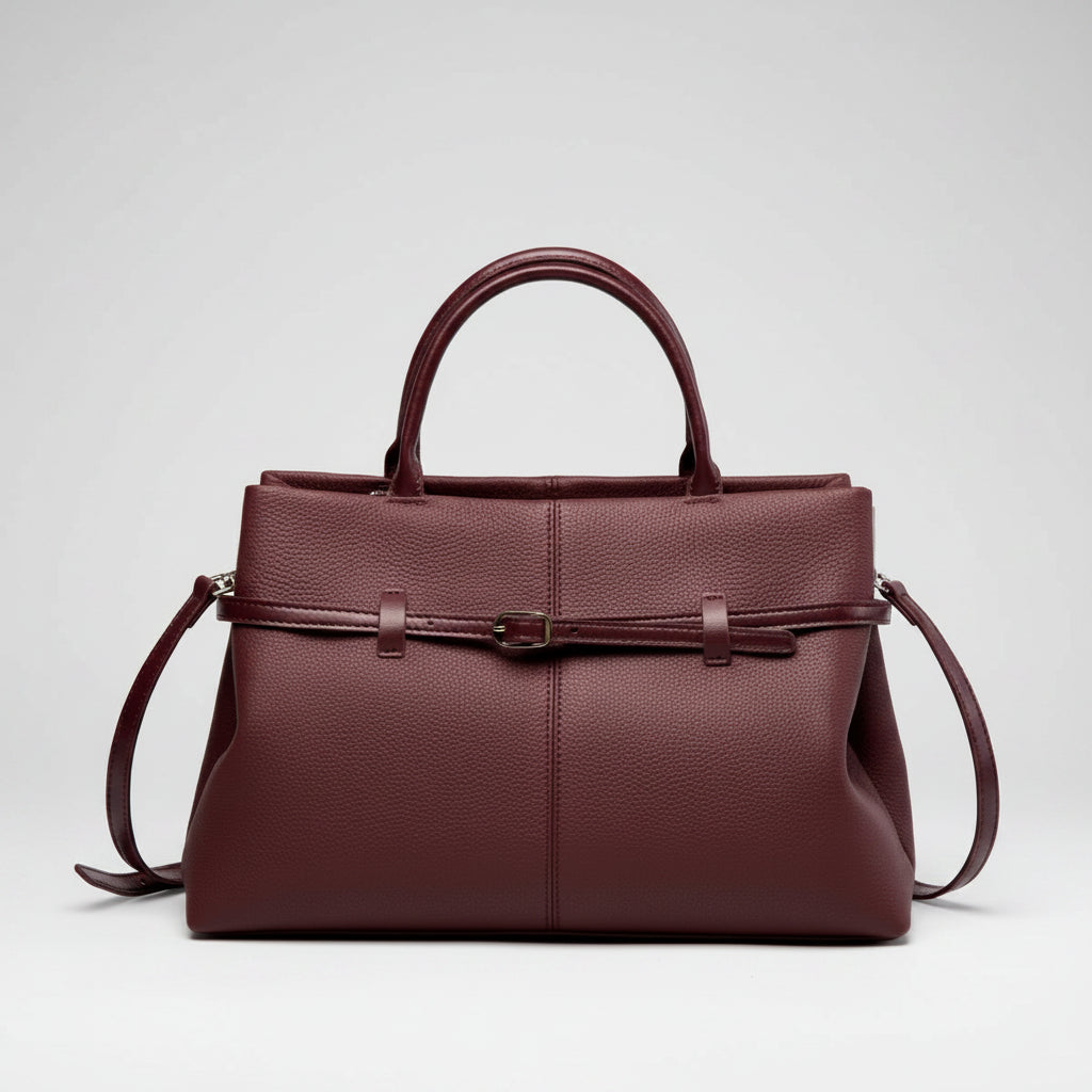 Front view of a wine red genuine leather tote bag with a sleek and sophisticated design, highlighted by the central buckle accent