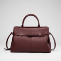 Front view of a wine red genuine leather tote bag with a sleek and sophisticated design, highlighted by the central buckle accent