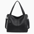 Front view of a black vegan leather tote bag with minimalist design, complemented by sturdy straps and a tassel detail