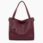 Front view of the wine red vegan leather tote bag featuring a minimalist design with a central tassel detail and elegant handles