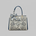 Front view of the Elisandra embroidered tote bag showcasing an intricate floral embroidery design with a stylish blue bow on the handle