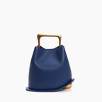 Front view of a Blue Izelia top grain leather crossbody bag with a gold handle on a white background
