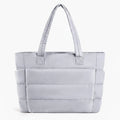 Front view of grey puffer-style tote bag with quilted texture and comfortable handles, ideal for everyday use