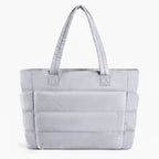 Front view of grey puffer-style tote bag with quilted texture and comfortable handles, ideal for everyday use