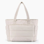 Front view of off-white puffer-style tote bag with soft quilted texture and durable handles for versatile use