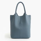 Front view of blue cowhide leather tote bag with minimalist design, featuring a central seam and sturdy handles