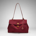 Front view of red velvet satchel bag featuring two gold clasps and a structured design