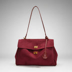 Front view of red velvet satchel bag featuring two gold clasps and a structured design