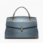 Front view of blue crocodile leather satchel bag featuring a gold clasp and glossy textured finish