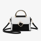 Front view of the black and white vegan leather satchel bag with a unique geometric design, featuring a gold-tone metal clasp